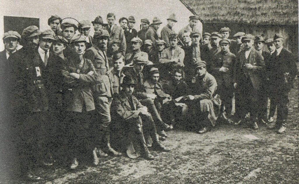 Oddział Dywersyjny kpt. Tadeusza Puszczyńskiego ps. Wawelberg w III powstaniu śląskim. Fotografia wykonana w Pyskowicach w końcu czerwca 1921. Siedzą od lewej: 2 Stefan Mańkowski (z odkrytą głową), 3 Michał Kaczorowski (w czapce), 4. Tadeusz Puszczyński (w kapeluszu). Stoją w I rzędzie od lewej: 1 Stanisław Sachs (z latarką na piersi), 2 Tadeusz de Nisau, 4 Bohdan de Nisau. Stoją w I rzędzie od prawej: 4 Stanisław Baczyński (w czapce nieco wyższy), 5 Dobiesław Damięcki (z rozwichrzoną czupryną). W II rzędzie od lewej 4 Stanisław Dubois (daszek czapki obrócony w lewo), W II rzędzie od prawej: Kazimierz Kuszel (z papierosem), W III rzędzie od lewej 5 Stanisław Leśniewski. | Źródło: domena publiczna (Wikimedia Commons)