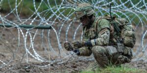 Zdjęcie główne: Brytyjski żołnierz umieszczający ładunki bangalore na zasiekach | Fot. Corporal Rob Kane/MOD (Open Government Licence v3.0)